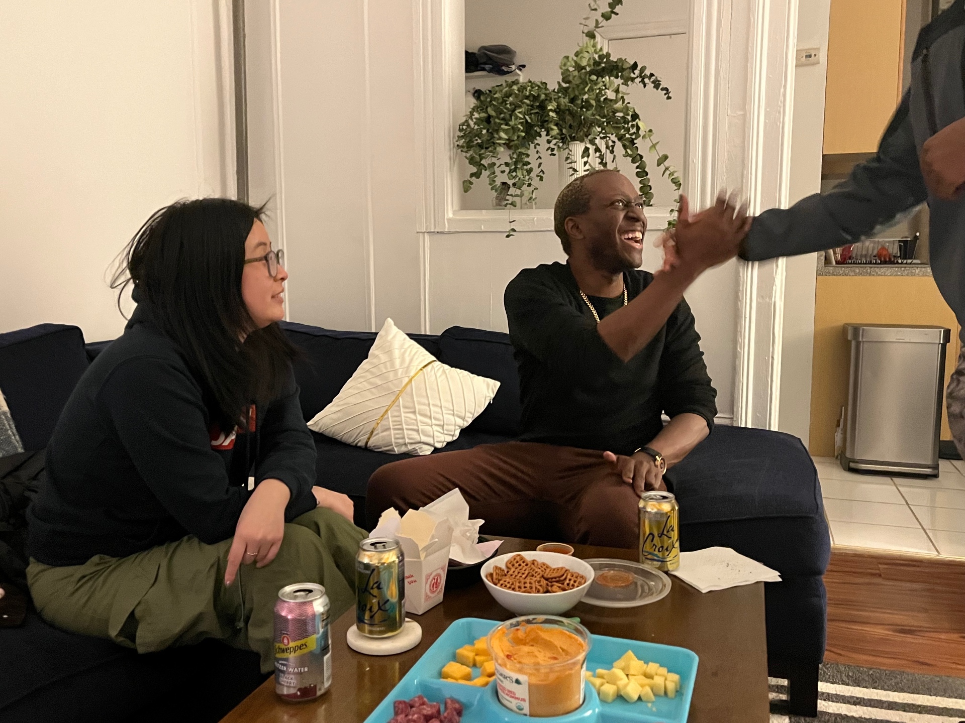 Two Hearth members laughing together on a couch during a small-group check-in.